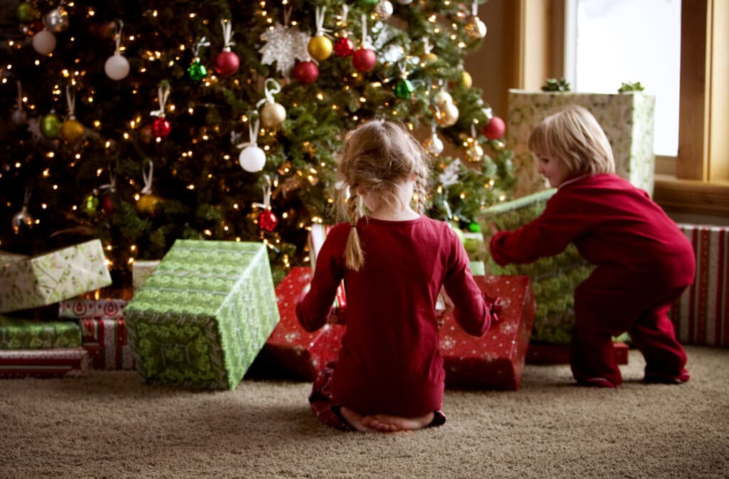 Děti u vánočního stromečku rozbalující si dárečky.