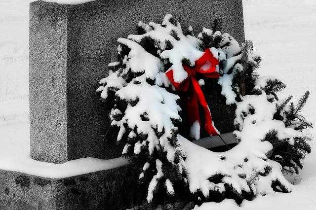 Zasněžený vánoční věnec jako dekorace na hrobě