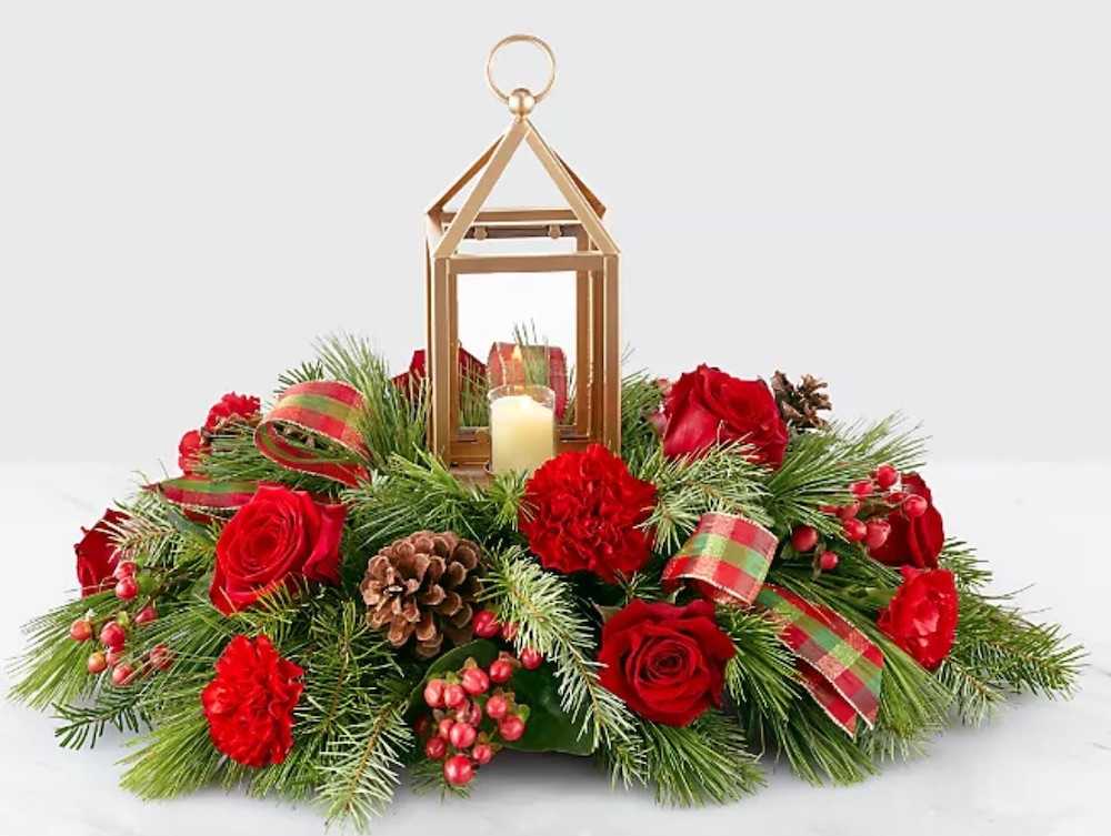 Vánoční aranžmá doplněné lucernou se svíčkou jako dekorace na hrob