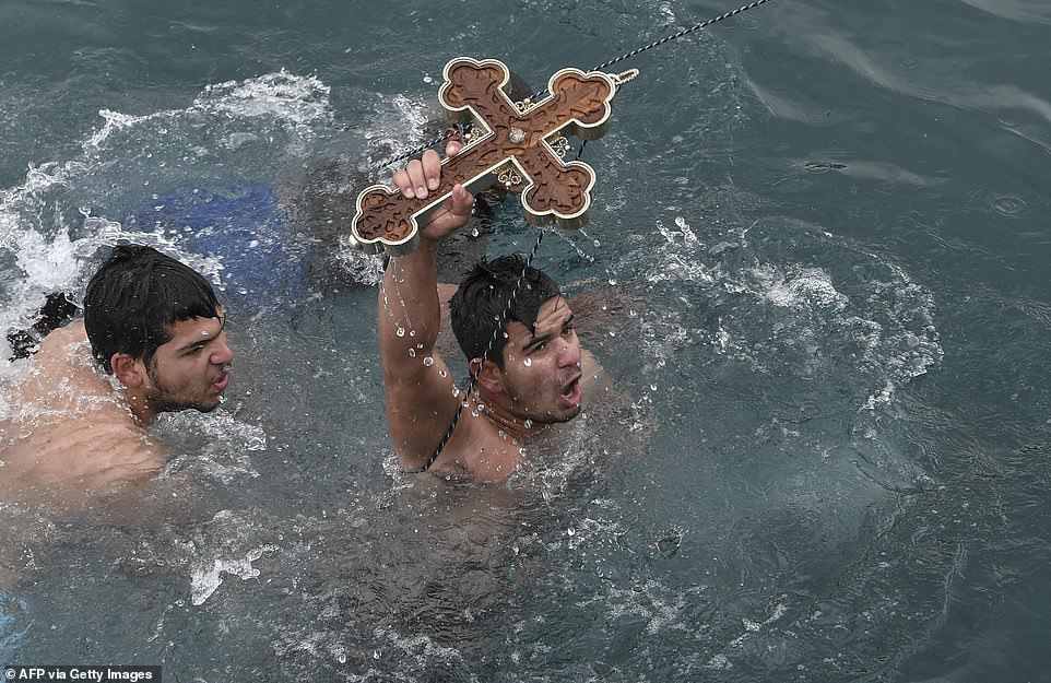 Muži potápějící se pro kříž na svátek Epifanie