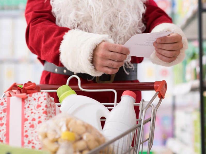 Santa s papírkem se seznamem věcí k nakoupení s nákupním vozíkem v krámě