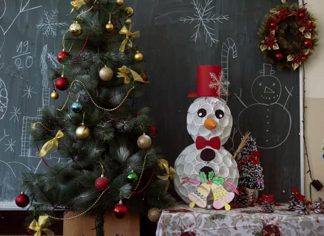 Vánoční stromeček a sněhulák před vánočně vyzdobenou školní tabulí.