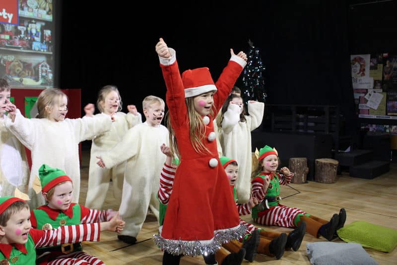 Besídkové představení školních dětí v převlecích za Santu, elfy a soby předvádějící vánoční hru