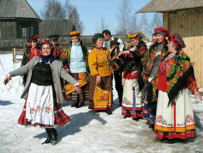 Skupina žen na vesnici v lidových krojích chystající se na tradiční koledu na Vánoce v Bělorusku