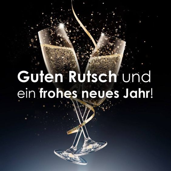 Dvě skleničky se šampaňským omotané stuhou a novoročním přáním v němčině