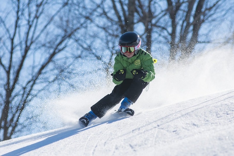 Chlapec divoce sjíždí svah na lyžích.