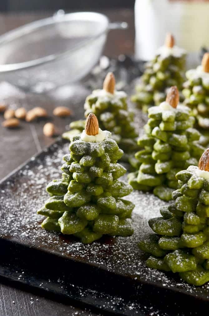 Zelené cukroví ve tvaru vánočního stromečku a ozdobené mandlí na plechu. 