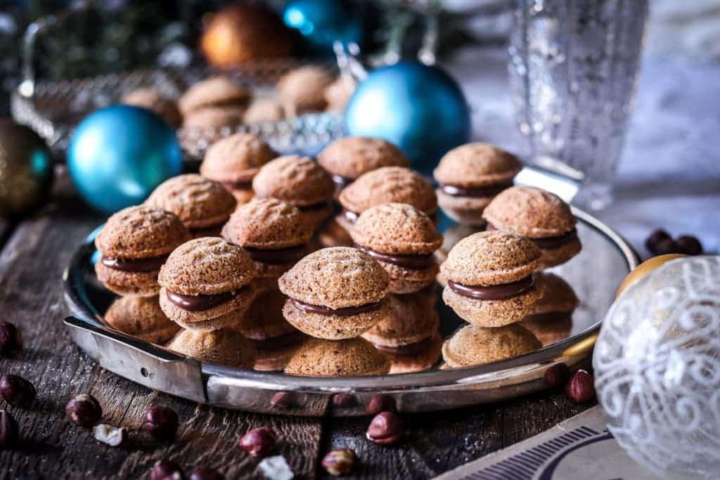 Vánoční ořechy z rýžové mouky a lískových ořechů plněné lísko-oříškovým krémem na tácu.
