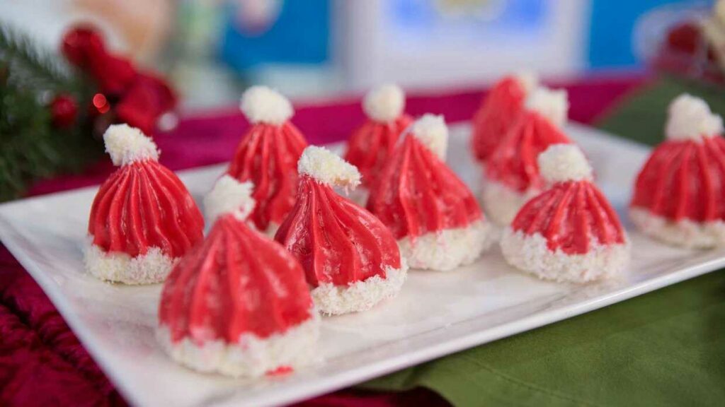 Vánoční pusinky ve tvaru čepiček Santa Clause na talířku.