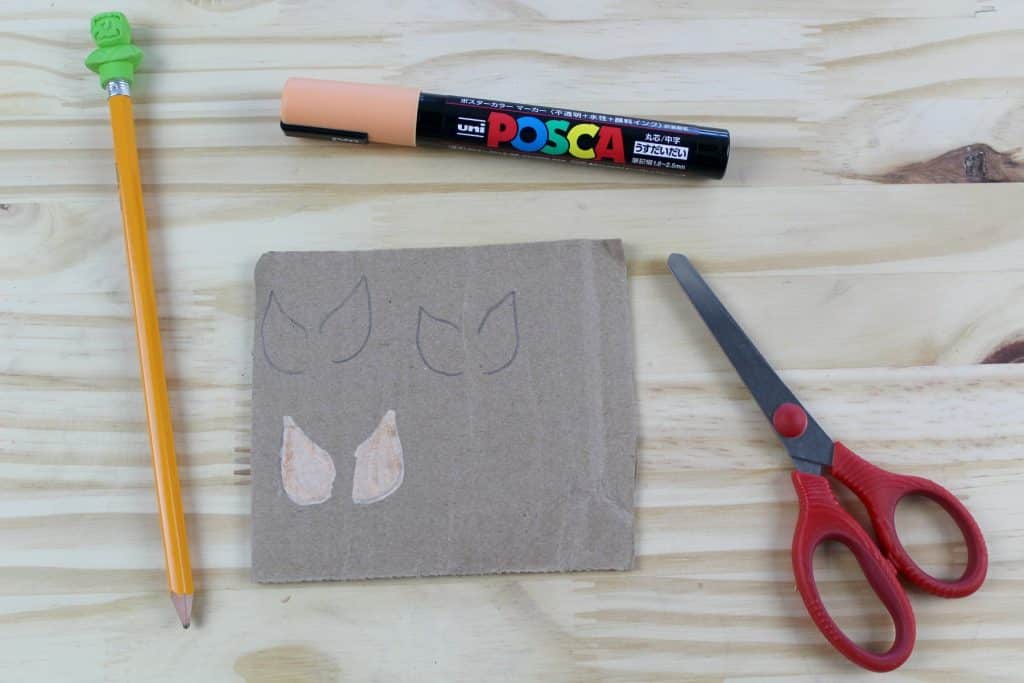 Tužka, fix, nůžky a kus kartonu s namalovanými křídly.