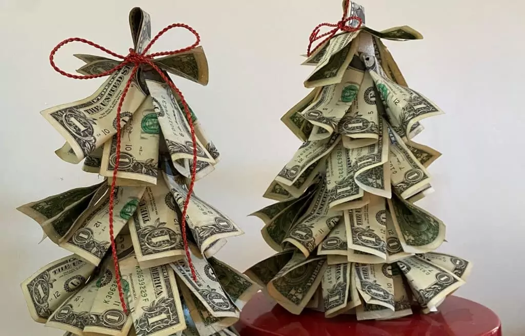 Vánoční stromek z bankovek, nahoře ovázaný stuhou.