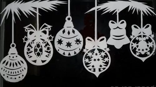 Okno ozdobené papírovou vánoční vystřihovánkou s ozdobami a zvonečkem